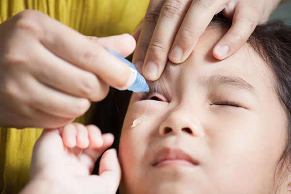 little girl getting eyedrops put in